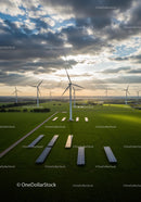 Wind Turbines and Solar Panels in Green Fields at Sunrise