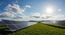 Solar Panels in Sunlit Field with Blue Sky and Clouds