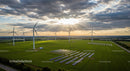 Wind Turbines and Solar Panels in Green Landscape at Sunset