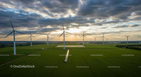 Wind Turbines Generating Power Over Green Fields at Sunset