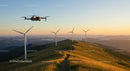 Drone Flying Over Wind Turbines on Grassy Mountain at Sunset