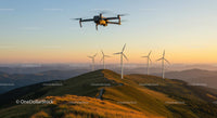 Drone Flying Over Wind Turbines at Mountainous Sunset