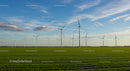 Wind Turbines on a Vast Green Field Under a Clear Blue Sky