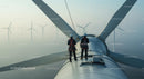 Engineers Inspecting Wind Turbine at Sunrise