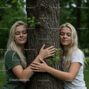 Two Young Women Embracing a Tree in Lush Green Forest