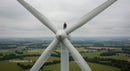 Technician Performing Maintenance on Wind Turbine Over Fields