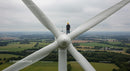 Engineer Inspecting Wind Turbine Above Green Fields