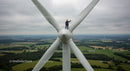 Aerial Technician Working on Wind Turbine Amidst Green Landscape