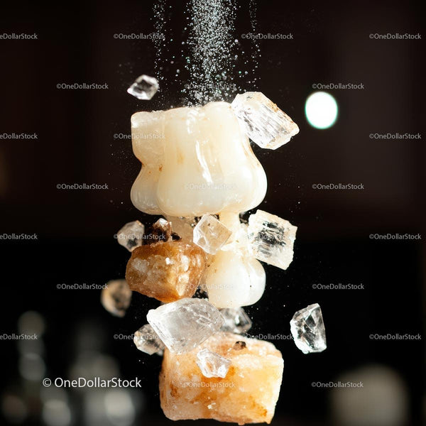 Close-Up of Falling Salt Crystals Against Dark Background