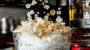 Ice Cubes Splashing into Whiskey Glass with Golden Liquor