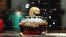 Ice Cube Falling into Glass of Fizzy Cola