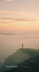 Solitary Figure Standing on Cliff at Misty Sunrise