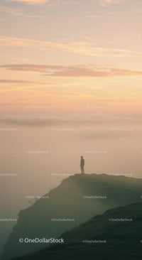 Solitary Figure Standing on Cliff at Misty Sunrise
