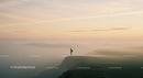 Solitary Figure Overlooking Foggy Cliffs at Sunrise