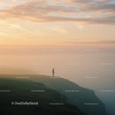 Solitary Figure Overlooking Cliff at Misty Sunrise