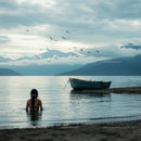 Woman and Boat in Tranquil Mountain Lake at Dusk