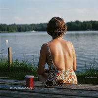Woman Relaxing by a Scenic Lake in Floral Swimsuit