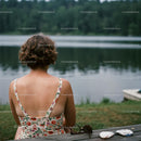 Woman in Floral Dress Relaxing by a Calm Forest Lake