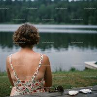 Woman in Floral Dress Relaxing by a Calm Forest Lake