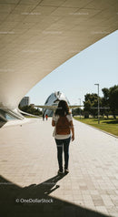 Young Woman Walking Near Modern Architectural Structure