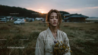 Pensive Woman Holding Yellow Wildflowers at Dusk