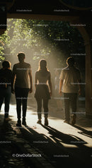 People Walking Through Sunlit Forest Path