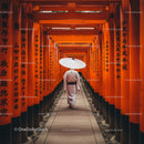 Person in Traditional Clothing Walking Through Orange Torii Gates