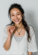 Joyful Woman Holding Necklace with a Bright Smile
