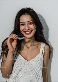 Smiling Woman Holding Teeth Aligner in White Knit Top