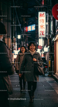 Smiling Friends Walking Through Vibrant City Streets at Night