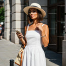 Chic Woman in White Dress and Hat in Urban Setting