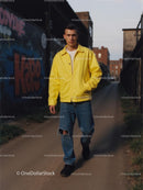 Young Man in Yellow Jacket Walking by Graffiti Wall