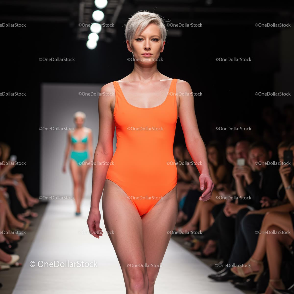 Modelka w jaskrawo pomarańczowym kostiumie kąpielowym na wybiegu