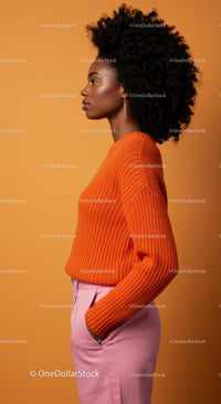 Stylish Woman in Orange Sweater with Afro Hair on Orange Background