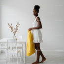 Elegant Woman in White Dress Holding Yellow Jacket Indoors