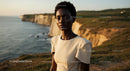 Elegant Woman Posing by Majestic Coastal Cliffs at Sunset