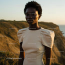 Woman in Elegant Dress at Sunset on Coastal Cliffs