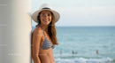 Smiling Woman in Striped Bikini and Sun Hat by the Beach