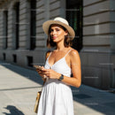 Woman in White Summer Dress with Sun Hat and Smartphone
