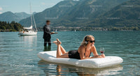 Woman Relaxing on Inflatable Mattress with Wine by Mountain Lake