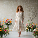 Woman in Flowing Dress Surrounded by Vibrant Flowers