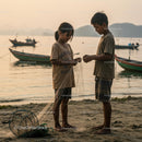 Children Fixing Fishing Net by the Sea at Sunset