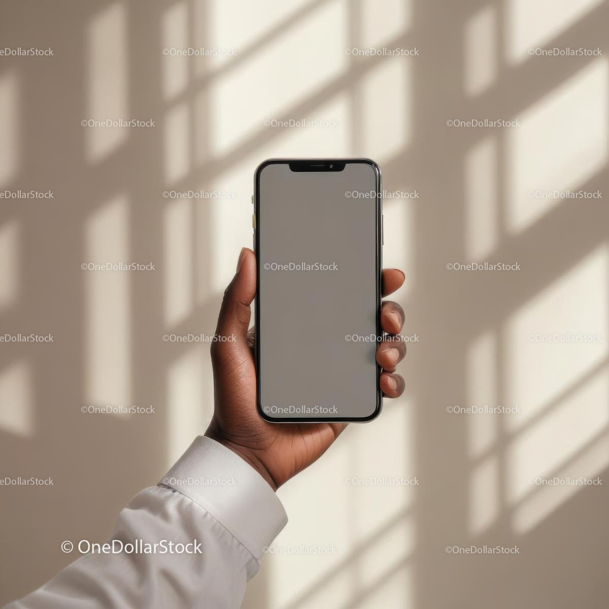 Ręka trzymająca smartfon w miękkim świetle z cieniami