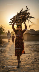 Young Girl Balancing Firewood at Sunset in Rural Village