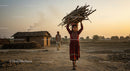 Young Girl Carrying Firewood in Rural Village at Sunset