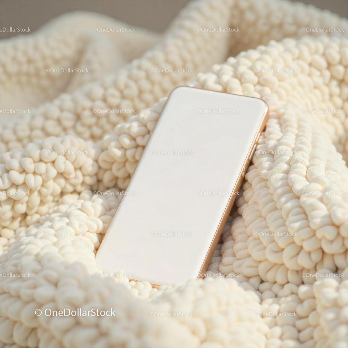 Smartfon leżący na przytulnym, beżowym kocu o fakturze