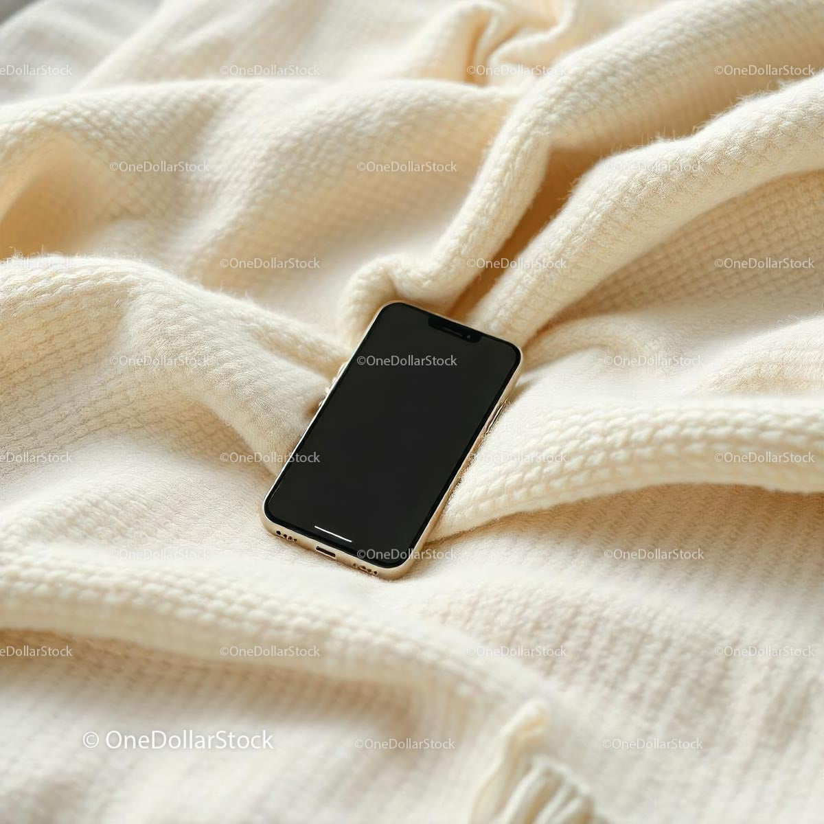 Smartfon spoczywający na przytulnym beżowym kocu