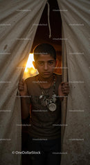 Young Boy Standing at Tent Entrance During Golden Sunset