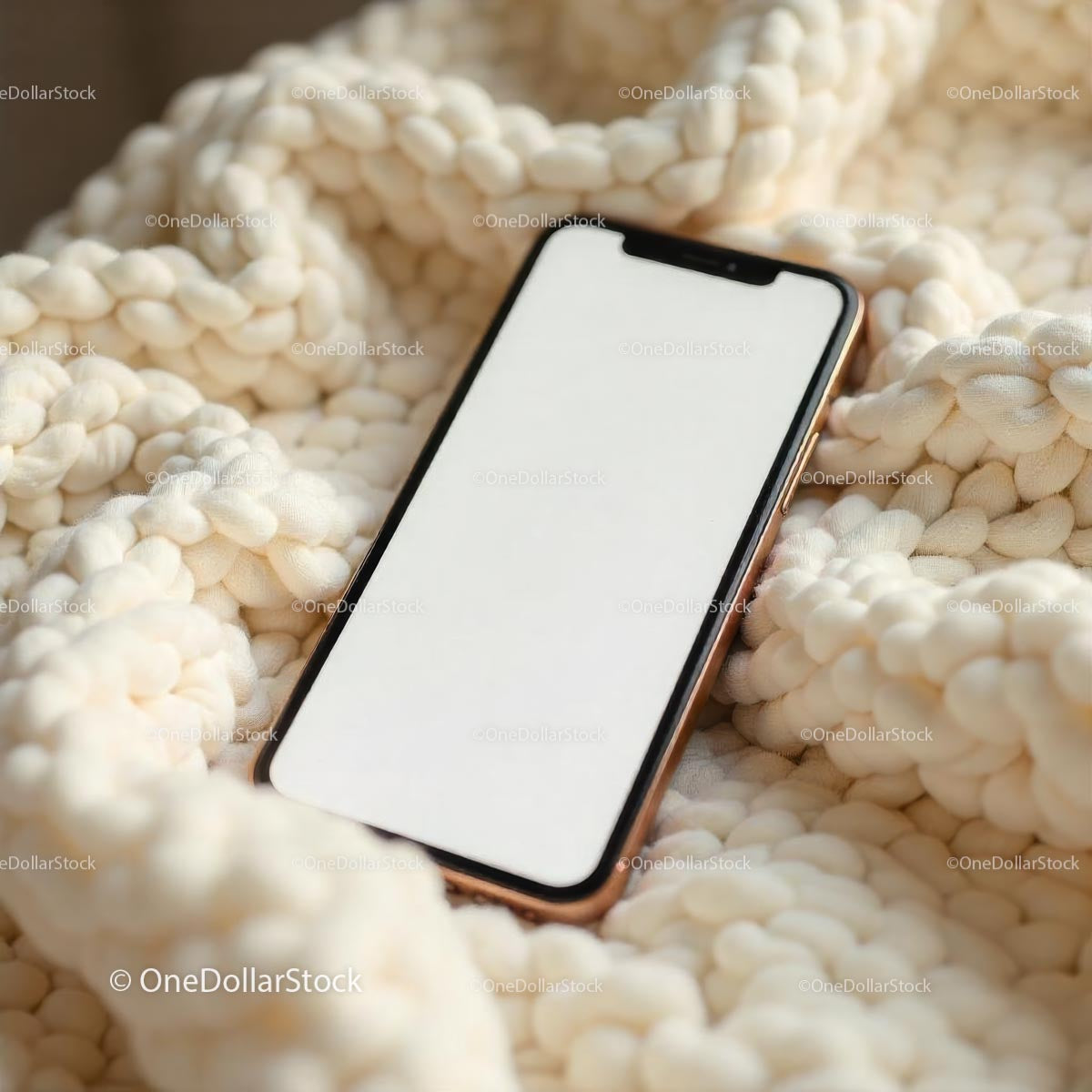 Smartfon leżący na kremowym kocu dzianinowym