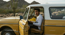 Young Man in Vintage Car Holding Yellow Sneakers in Desert